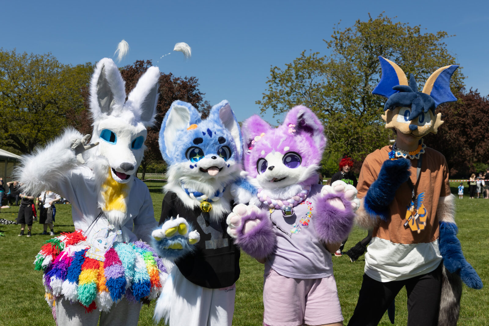 Four fursuiters posing together on the grass at Pups in the Park
